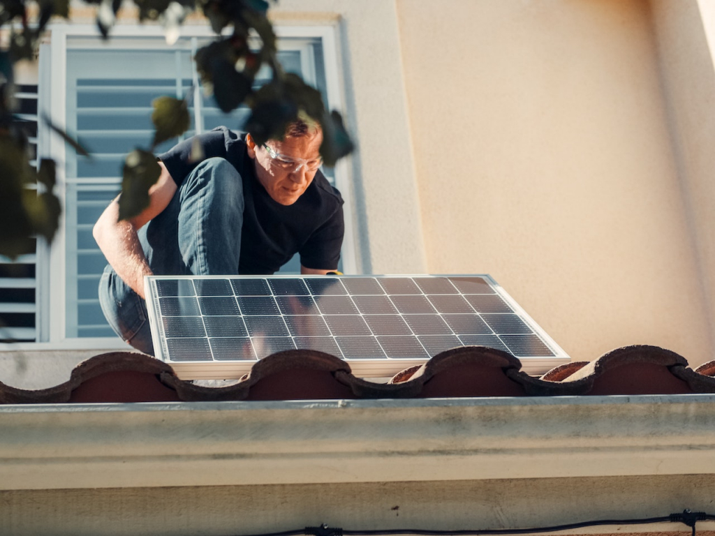 A man fixing a solar panel onto the roof.