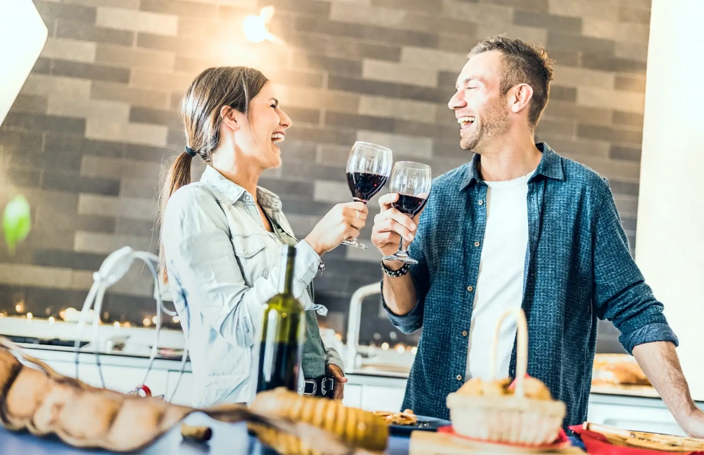 Man and Woman as Couple Smiling Holding Wine Glasses in Kitchen